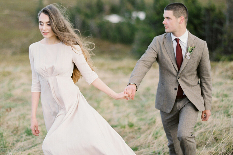 Destination Wedding Photographer in Italy: Young couple holding hands walking along the valley